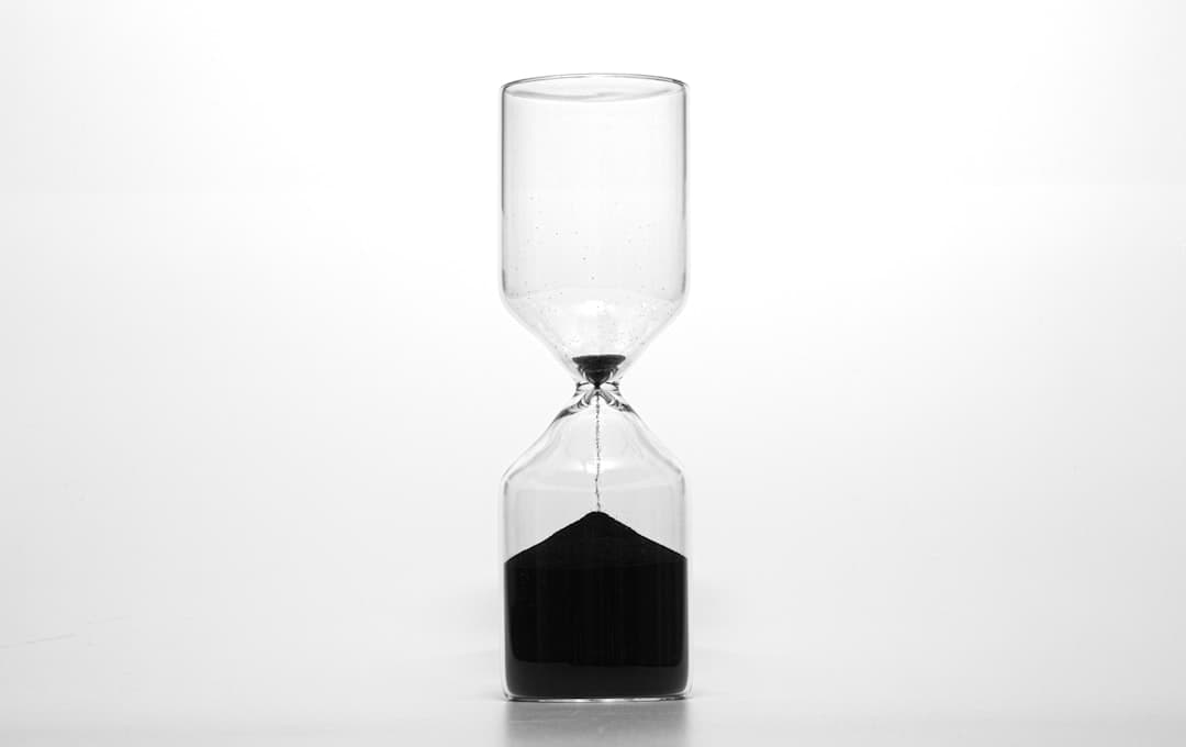 Sablier en verre transparent avec sable noir, illustrant la durée d'un projet de création de site web